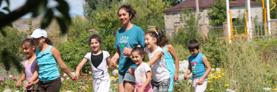 Discover Armenia participant holding children's hands in a field in Armenia