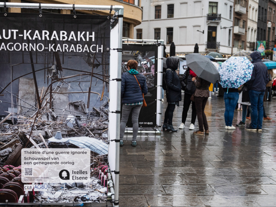 Outdoor photo exhibition with people looking at prints in the rain