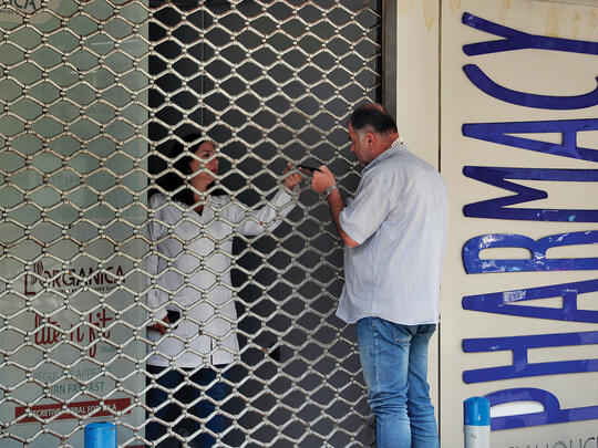A customer speaks with a pharmacist through a locked door after pharmacies across Lebanon began a two-day strike protesting severe shortages in medicinal supplies that is increasingly putting them in confrontation with customers and patients searching for medicines. June 2021.