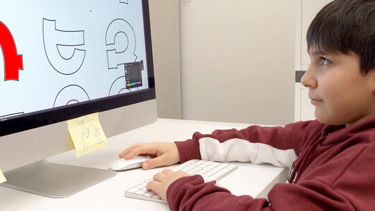 A kid coloring the Armenian Alphabet on a pc